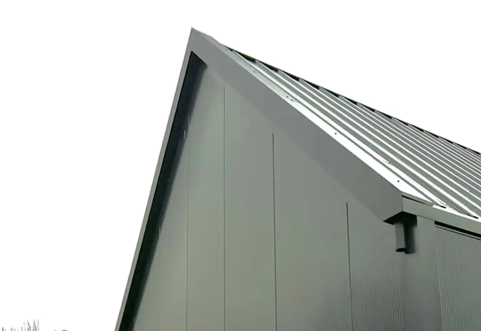 Grote duurzame schuur naast woning met puntdak